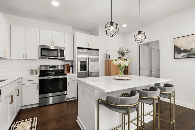 a kitchen with stainless steel appliances kitchen island granite countertop a dining table and chairs