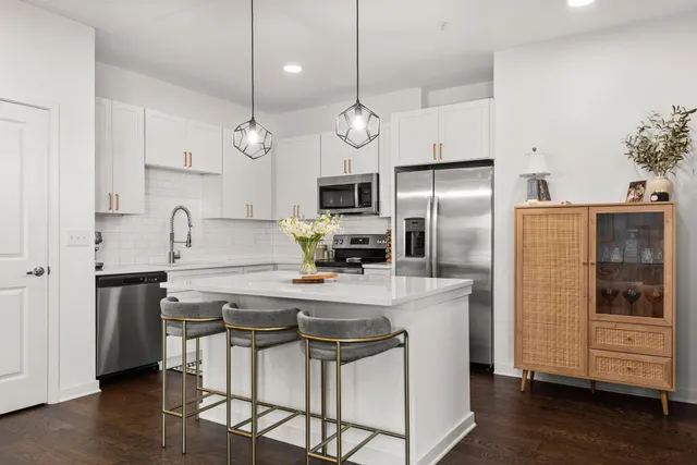 a kitchen with stainless steel appliances a refrigerator a stove a sink and white cabinets