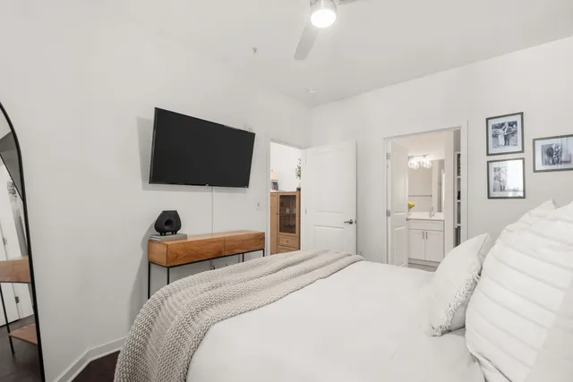 a bedroom with a bed and a flat tv screen on wall