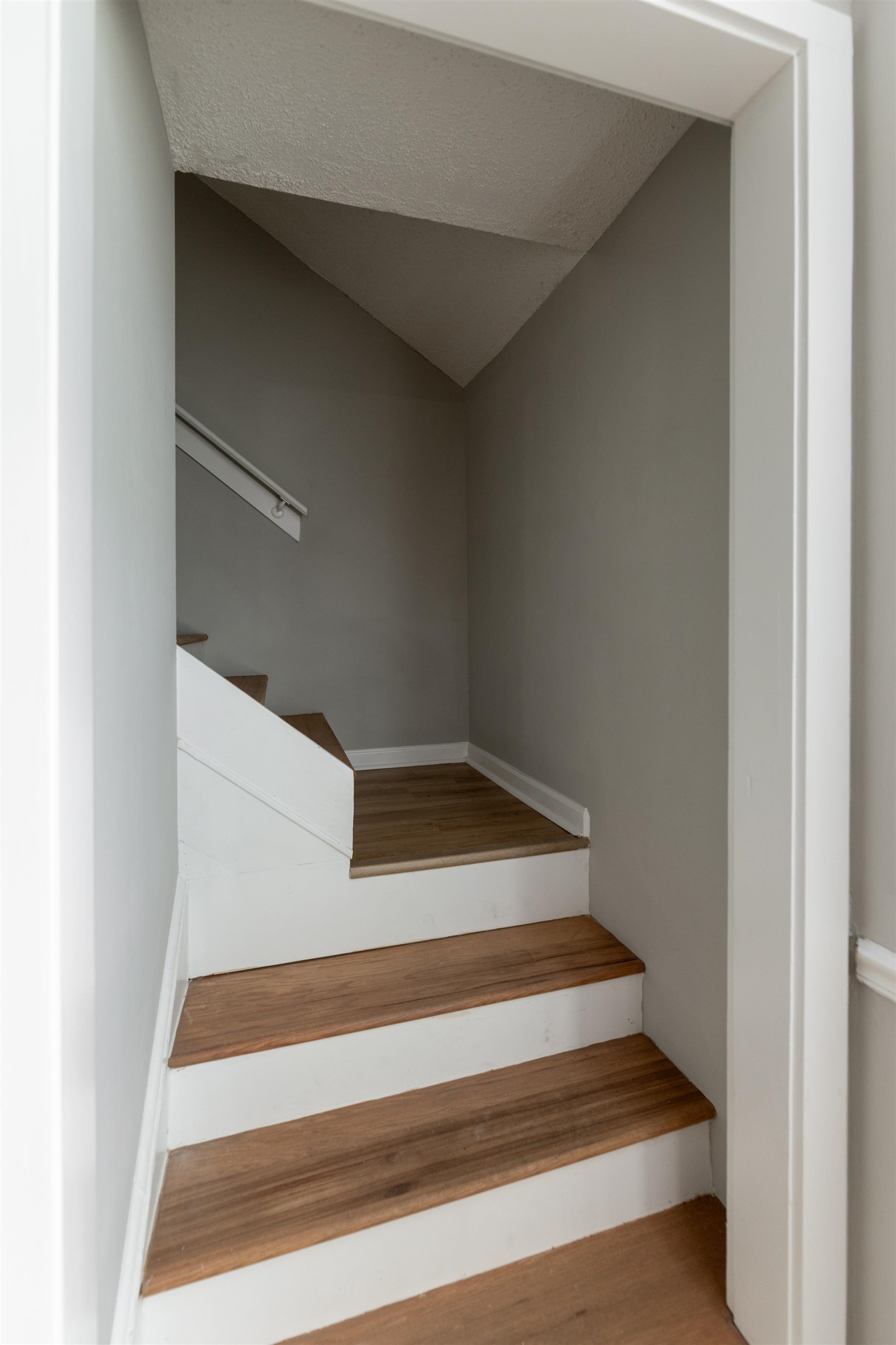 7421 Richmond Road Memphis, TN 38125 - Photo 30 of 39 Staircase featuring wood-finish treads, white risers, and a white handrail set against light gray walls