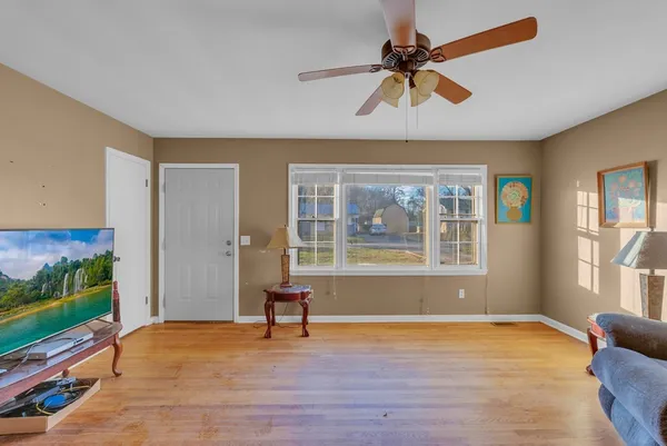 a view of an empty room with window and wooden floor