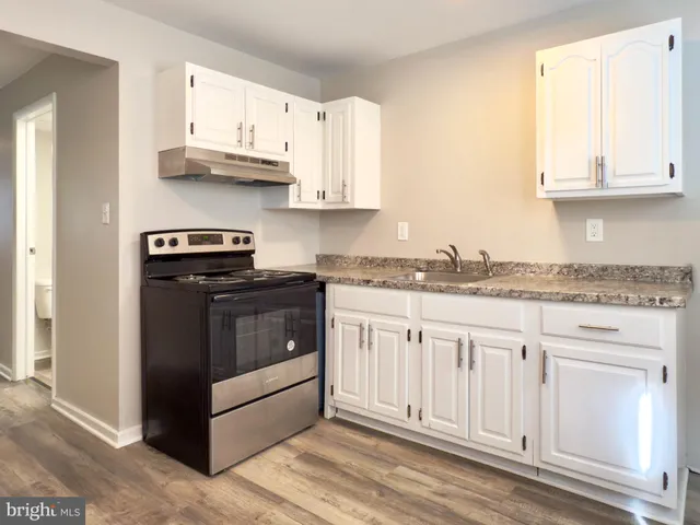a kitchen with granite countertop white cabinets and stainless steel appliances