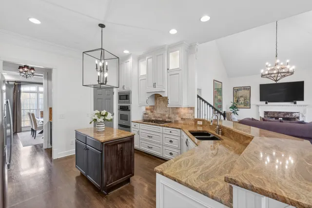 a living room with furniture kitchen view and a chandelier