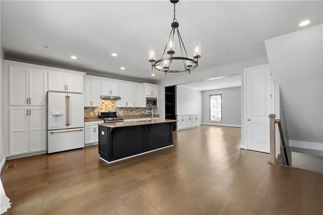 a kitchen with stainless steel appliances granite countertop a refrigerator a stove a sink dishwasher a oven with white cabinets and wooden floor