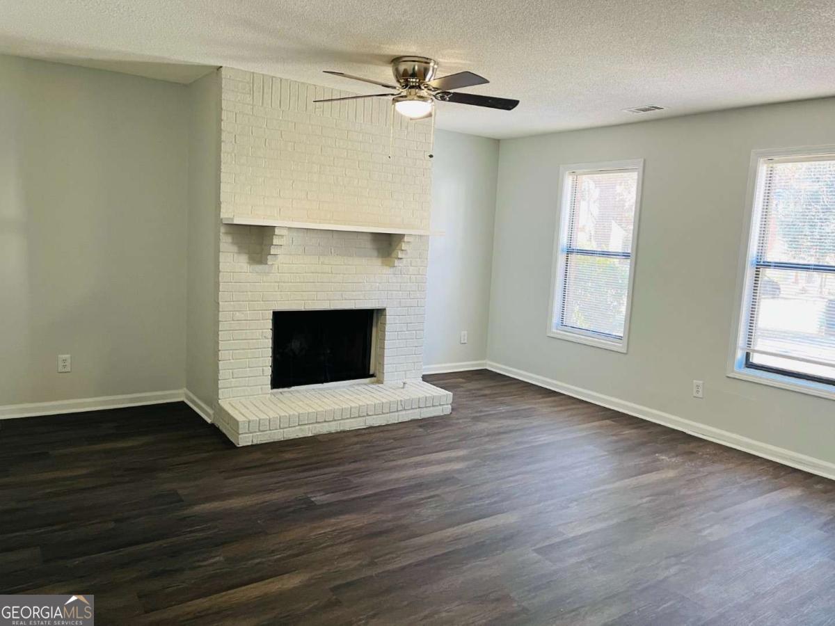 5614 Windwood Road, Unit 5614 Atlanta, GA 30349 - Photo 3 of 26 an empty room with wooden floor a fireplace and windows