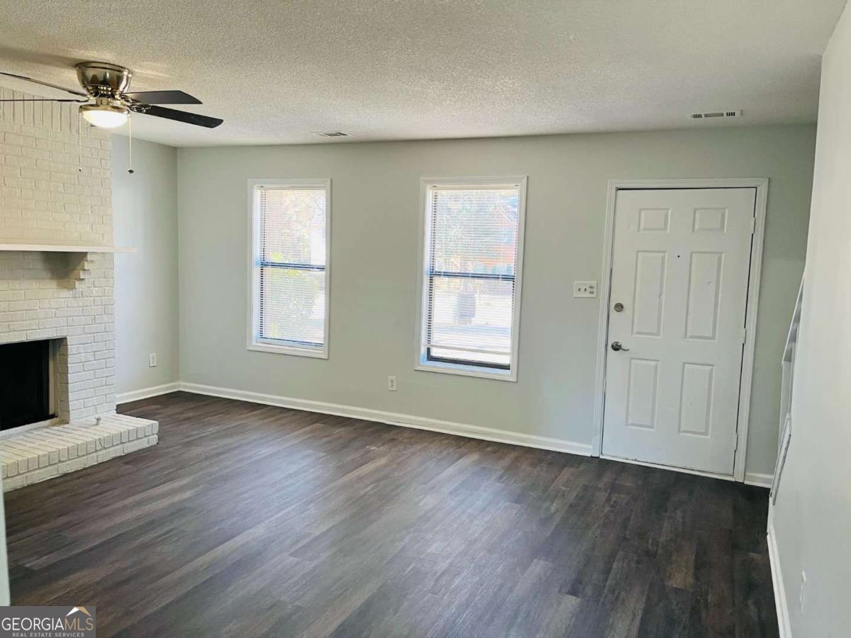 5614 Windwood Road, Unit 5614 Atlanta, GA 30349 - Photo 4 of 26 an empty room with wooden floor fireplace and windows
