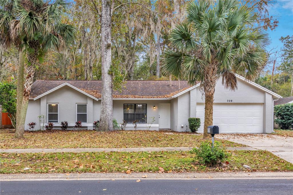a front view of house with yard and trees around