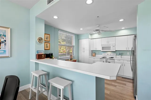 a kitchen with stainless steel appliances a stove a sink dishwasher a refrigerator and white cabinets with wooden floor