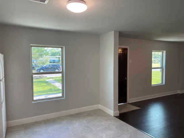 an empty room with wooden floor windows and closet
