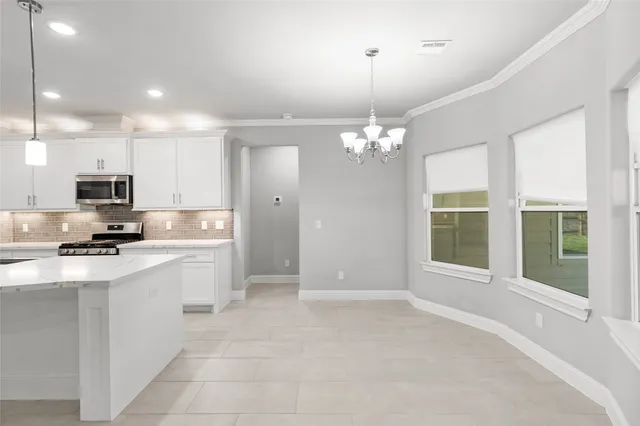 a large white kitchen with kitchen island a sink stainless steel appliances and cabinets