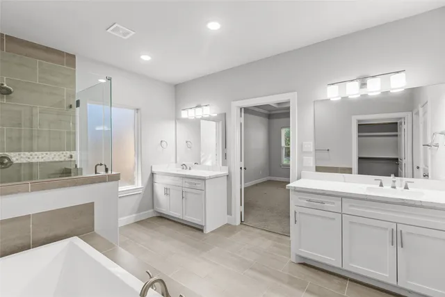 a large bathroom with a double vanity sink a large mirror and a bathtub