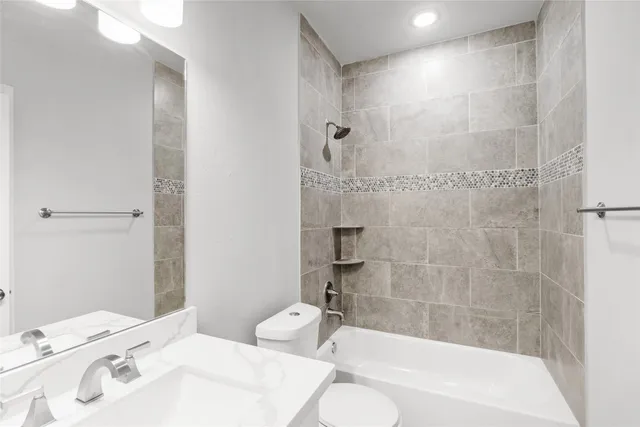 a bathroom with a bathtub shower sink vanity and toilet