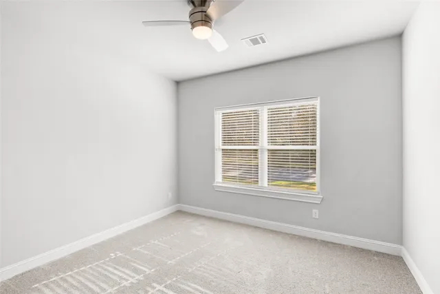 an empty room with a window and a fan