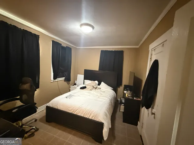 a bedroom with a bed a desk and chair with the wooden floor