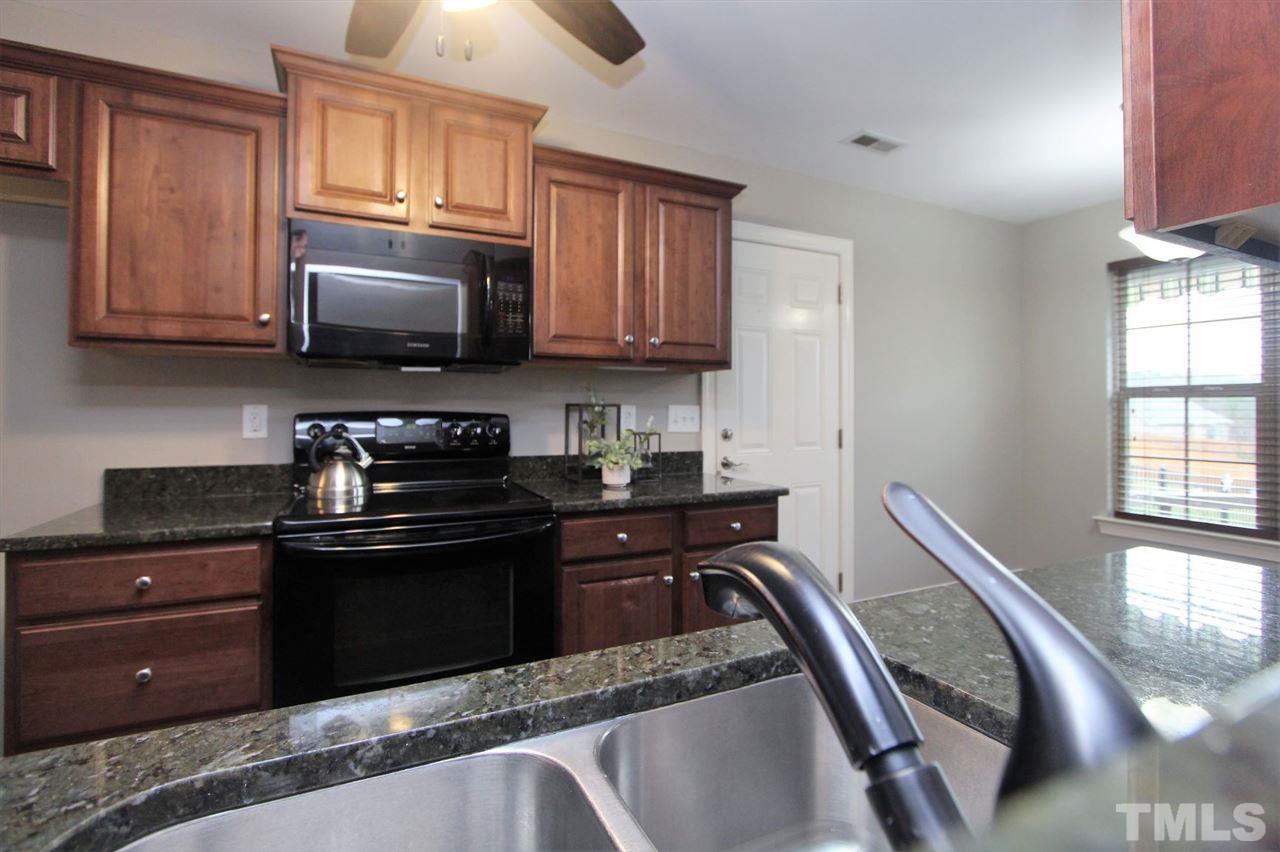 203 Orkney Road Stem, NC 27581 - Photo 12 of 30 a kitchen with granite countertop wooden cabinets and a stove top oven