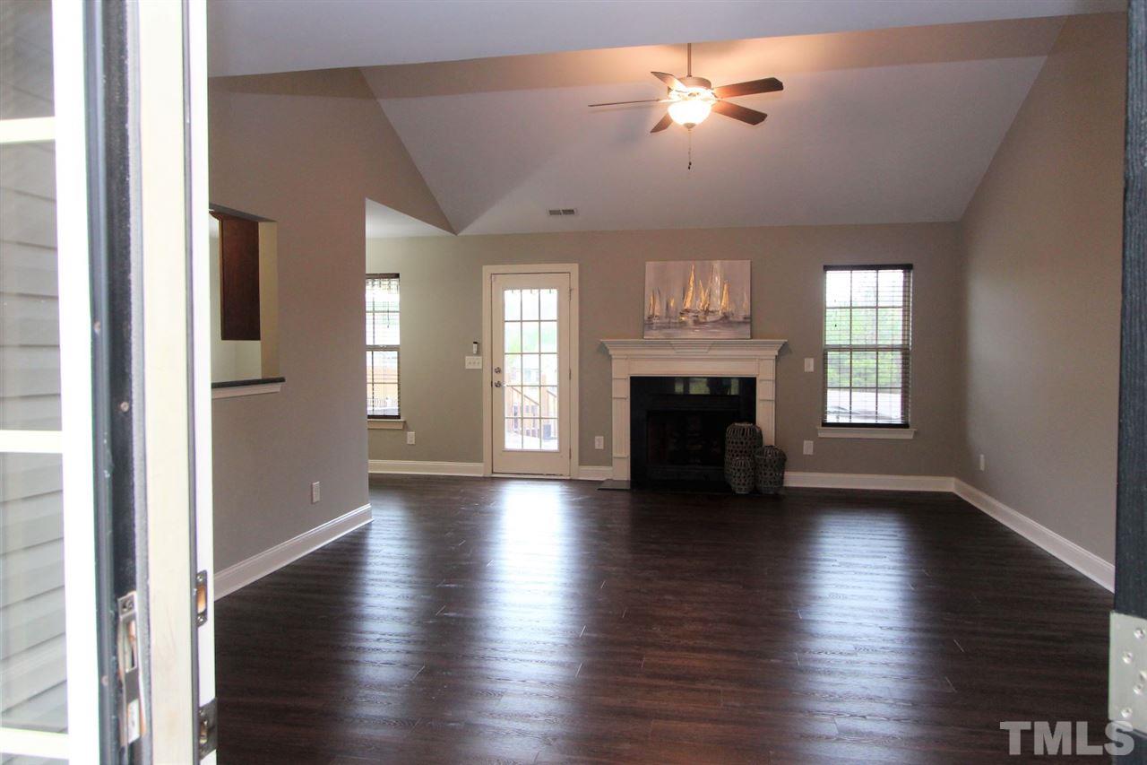 203 Orkney Road Stem, NC 27581 - Photo 5 of 30 an empty room with wooden floor fireplace and windows