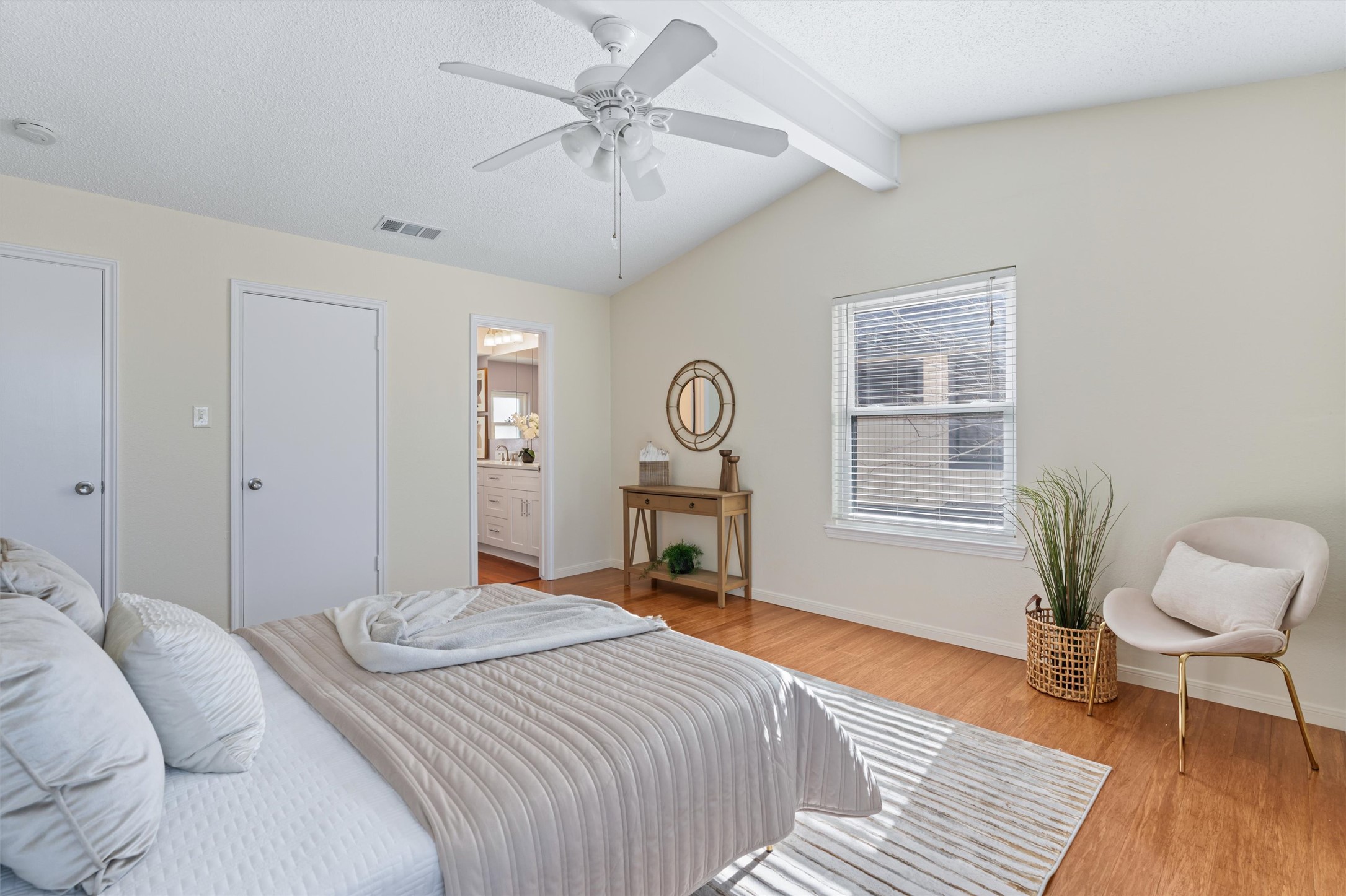 11902 Barrington Way Austin, TX 78759 - Photo 15 of 30 Primary bedroom featuring a closet, beamed ceiling, multiple windows, a textured ceiling, and light wood finished floors