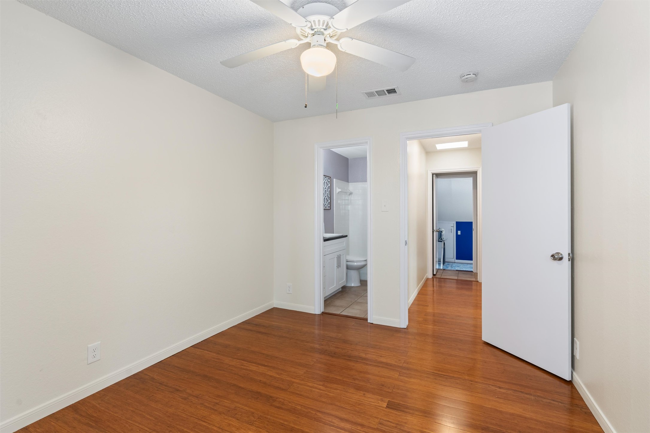 11902 Barrington Way Austin, TX 78759 - Photo 18 of 30 Second bedroom featuring wood finished floors, a ceiling fan, a textured ceiling, and connected bathroom