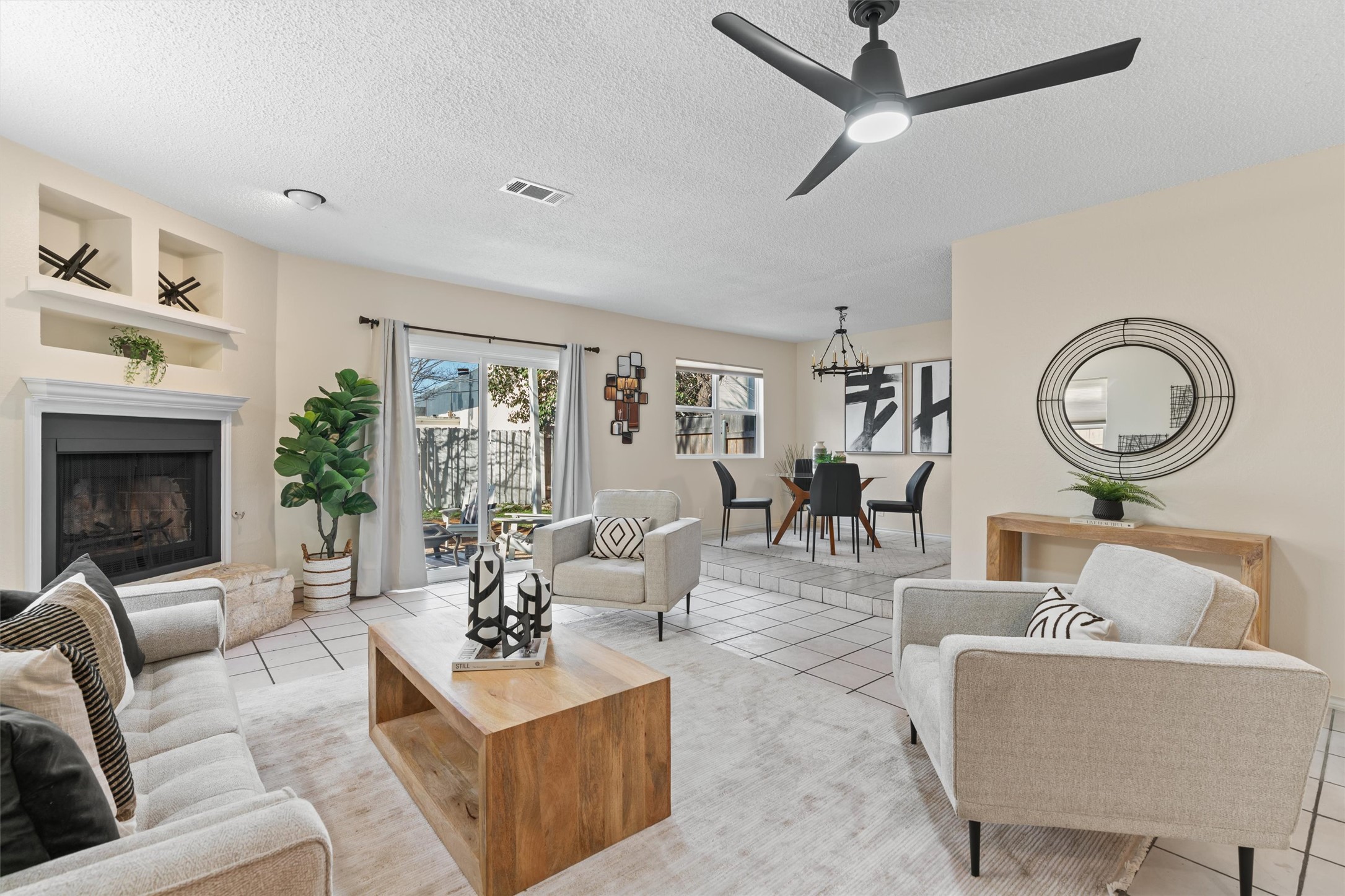 11902 Barrington Way Austin, TX 78759 - Photo 4 of 30 Living area with light tile patterned flooring, a textured ceiling, ceiling fan, and a fireplace with raised hearth