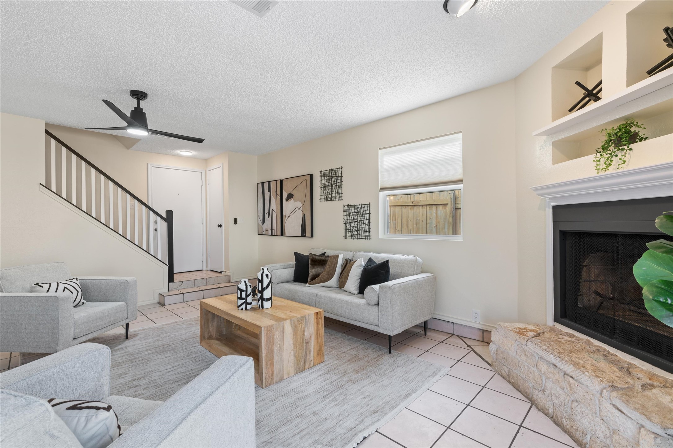 11902 Barrington Way Austin, TX 78759 - Photo 5 of 30 Living area featuring ceiling fan, a fireplace with raised hearth, light tile patterned floors, and a textured ceiling