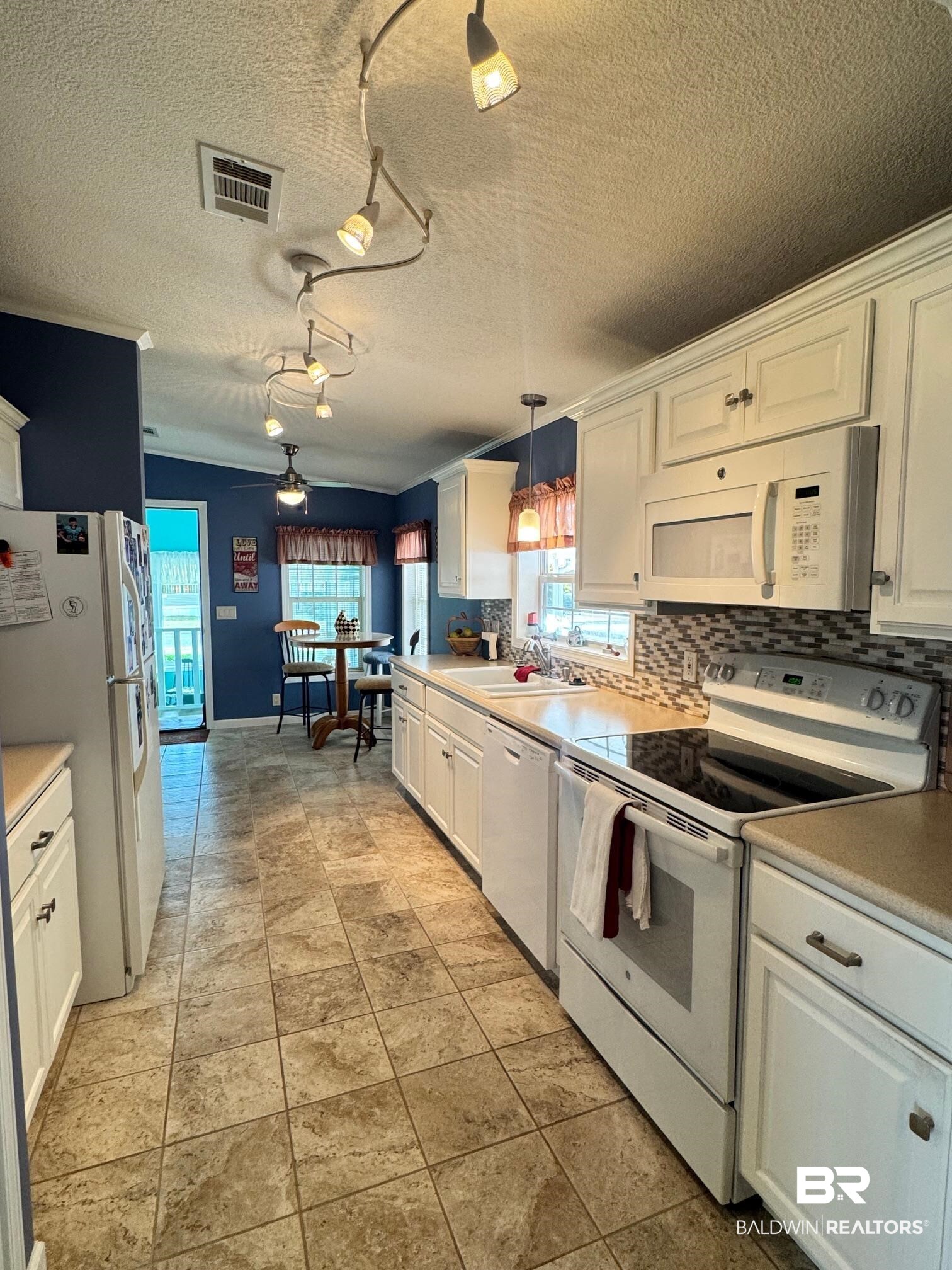 1165 Santa Anna Lane Lillian, AL 36549 - Photo 4 of 43 Kitchen with white appliances, visible vents, white cabinets, hanging light fixtures, and light countertops
