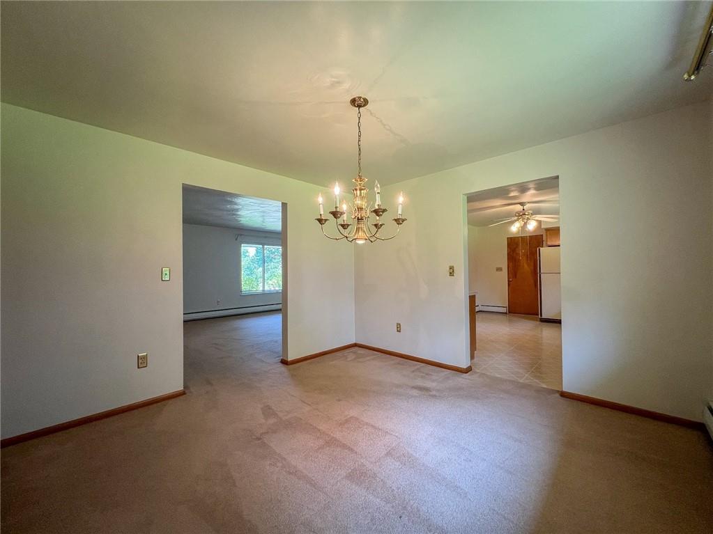 115 Grohman Road Butler, PA 16002 - Photo 8 of 39 an empty room with chandelier fan and kitchen view