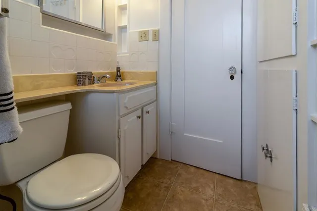 a bathroom with a granite countertop sink toilet and shower a mirror
