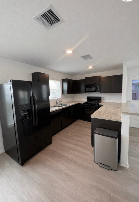 101 Cullen Street Angleton, TX 77515 - Photo 2 of 6 A modern kitchen features sleek black appliances, dark cabinetry, and light countertops.