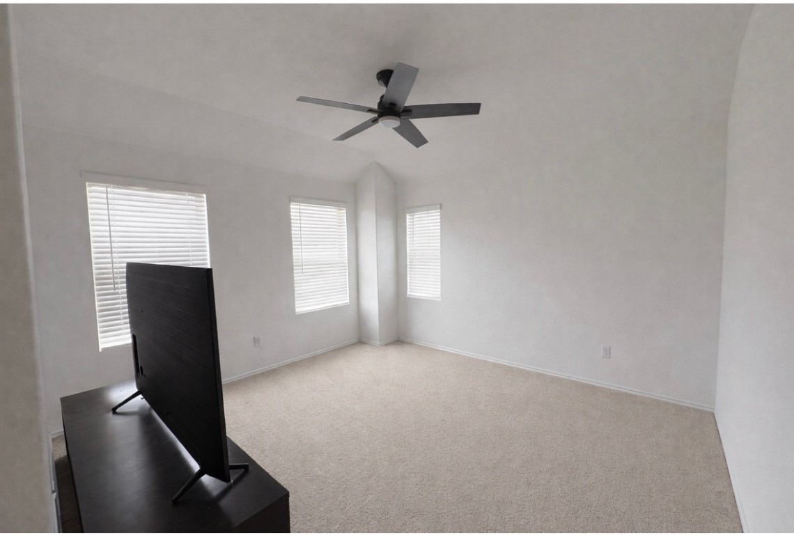 101 Cullen Street Angleton, TX 77515 - Photo 4 of 6 The up stairs gameroom is spacious and bright with neutral carpeting and white walls. It features a ceiling fan and two large windows with blinds, offering plenty of natural light.