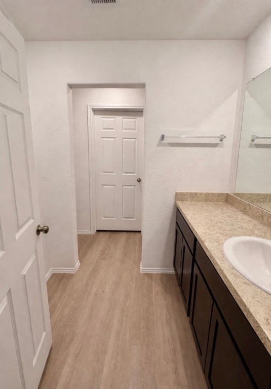 101 Cullen Street Angleton, TX 77515 - Photo 5 of 6 This primary bathroom features a modern design with light wood flooring, white walls, and a spacious vanity with a granite countertop and sink. A large mirror enhances the space, and there's ample storage in the dark cabinetry.