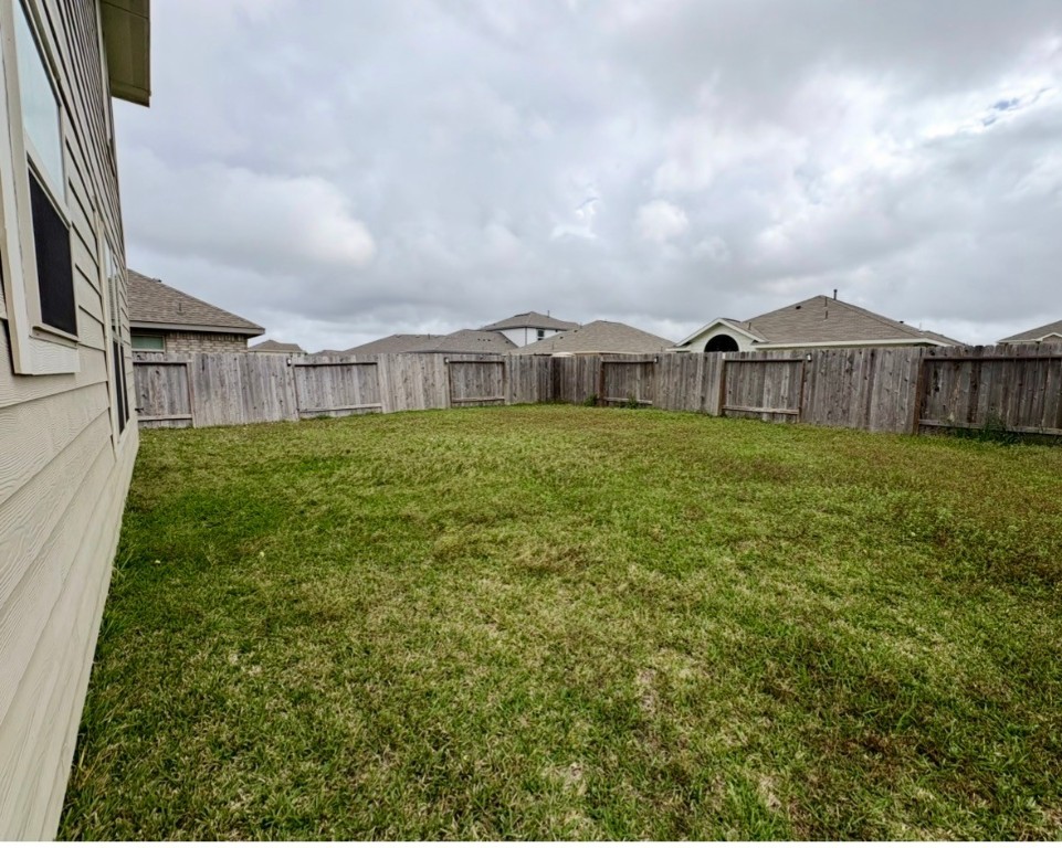 101 Cullen Street Angleton, TX 77515 - Photo 6 of 6 Spacious backyard with a well-maintained lawn, enclosed by a wooden fence, providing privacy and ample space for outdoor activities.