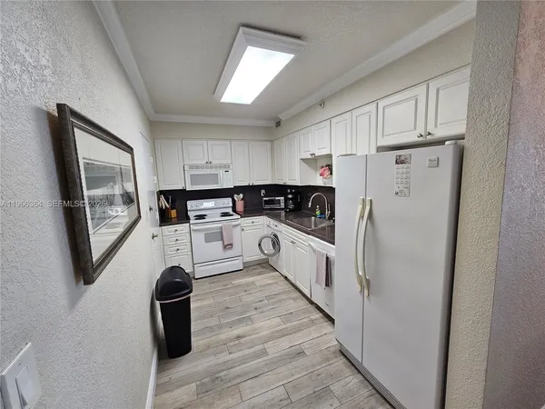 a kitchen with white cabinets and white appliances