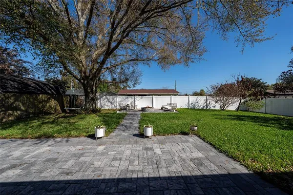 a view of a backyard with potted plants and large trees