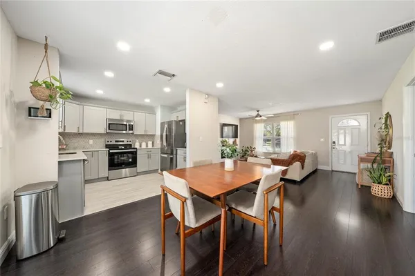 a kitchen with a dining table chairs wooden floor appliances and cabinets