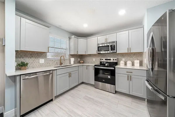 a kitchen with granite countertop a refrigerator stove top oven and sink