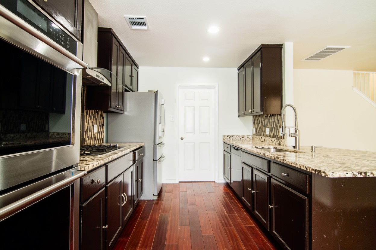 1431 Roxanne's Run Pflugerville, TX 78660 - Photo 11 of 29 Kitchen featuring stainless steel appliances, dark wood finish cabinets, dark wood-style floors, and recessed lighting