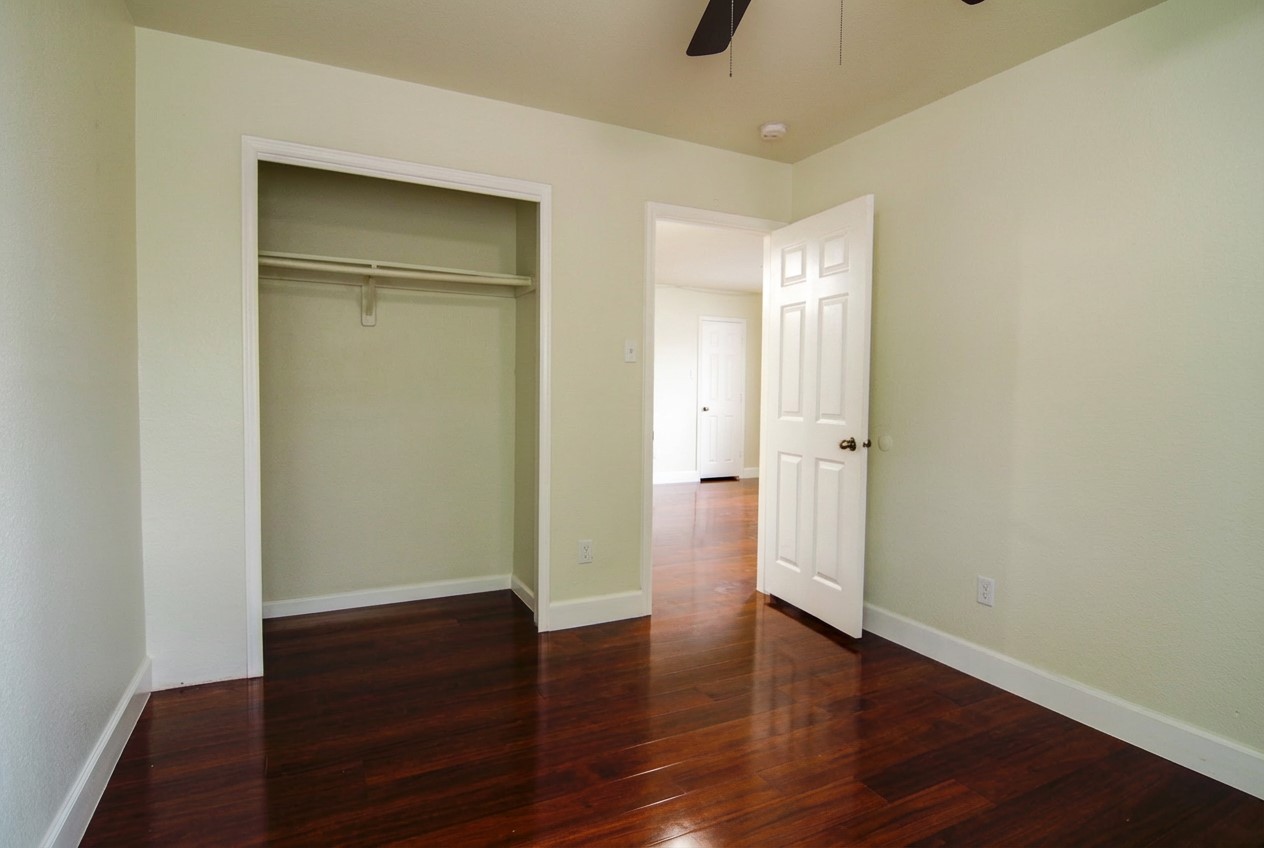 1431 Roxanne's Run Pflugerville, TX 78660 - Photo 17 of 29 Unfurnished bedroom featuring dark wood-style floors, ceiling fan, and a closet