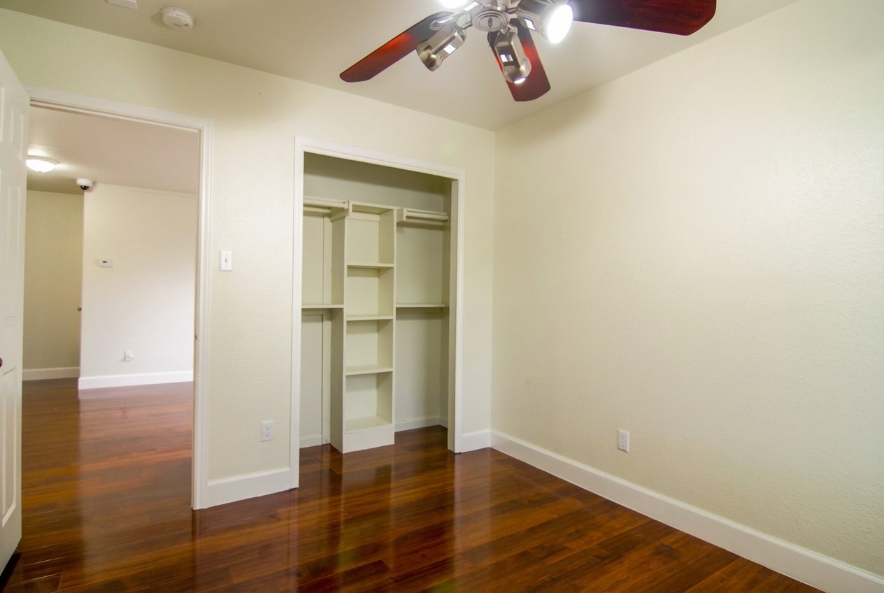 1431 Roxanne's Run Pflugerville, TX 78660 - Photo 19 of 29 Unfurnished bedroom featuring dark wood finished floors, a ceiling fan, and a closet
