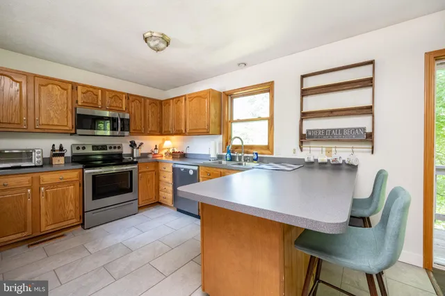 a kitchen with stainless steel appliances granite countertop a stove a sink a microwave a dining table and chairs