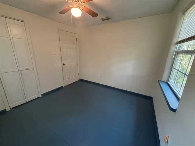 an empty room with windows and fan