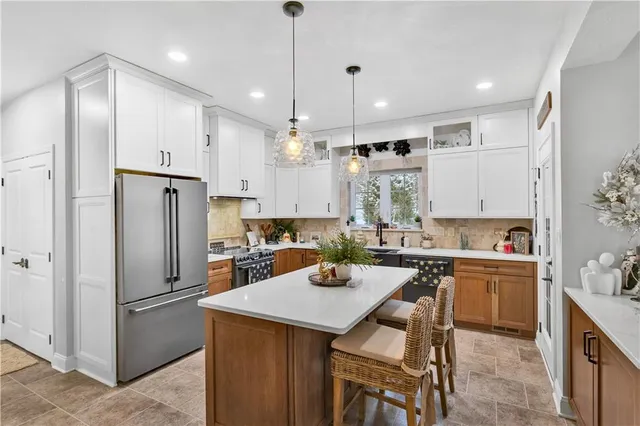 a kitchen with a refrigerator a sink a stove and chairs