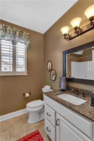a bathroom with a granite countertop sink mirror vanity and toilet