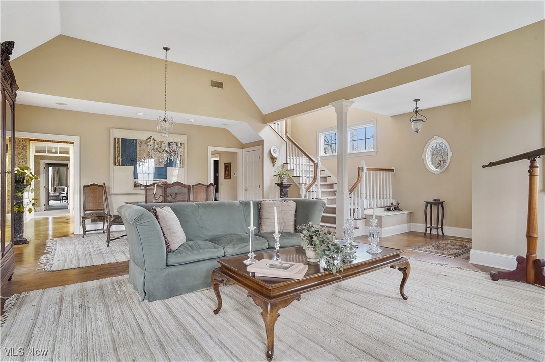 5612 Ridge Road Wadsworth, OH 44281 - Photo 5 of 33 Living room featuring ornate columns, a chandelier, high vaulted ceiling, and light hardwood / wood-style flooring