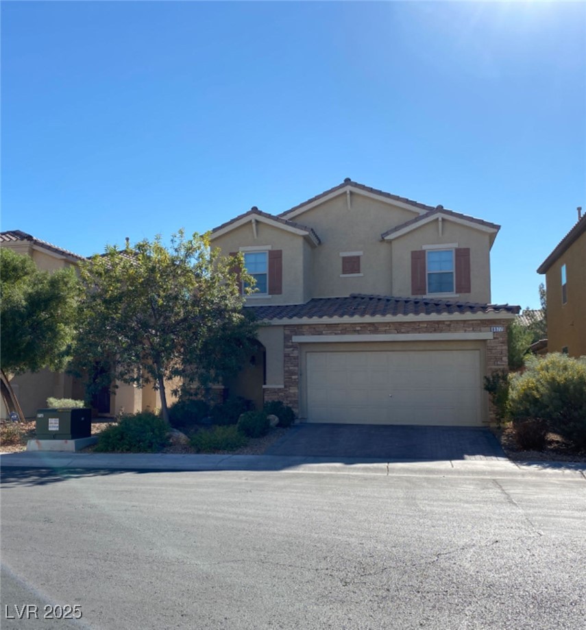 8977 Melridge Road Las Vegas, NV 89148 - Photo 2 of 35 Traditional-style house with a tile roof, stone siding, a garage, stucco siding, and concrete driveway