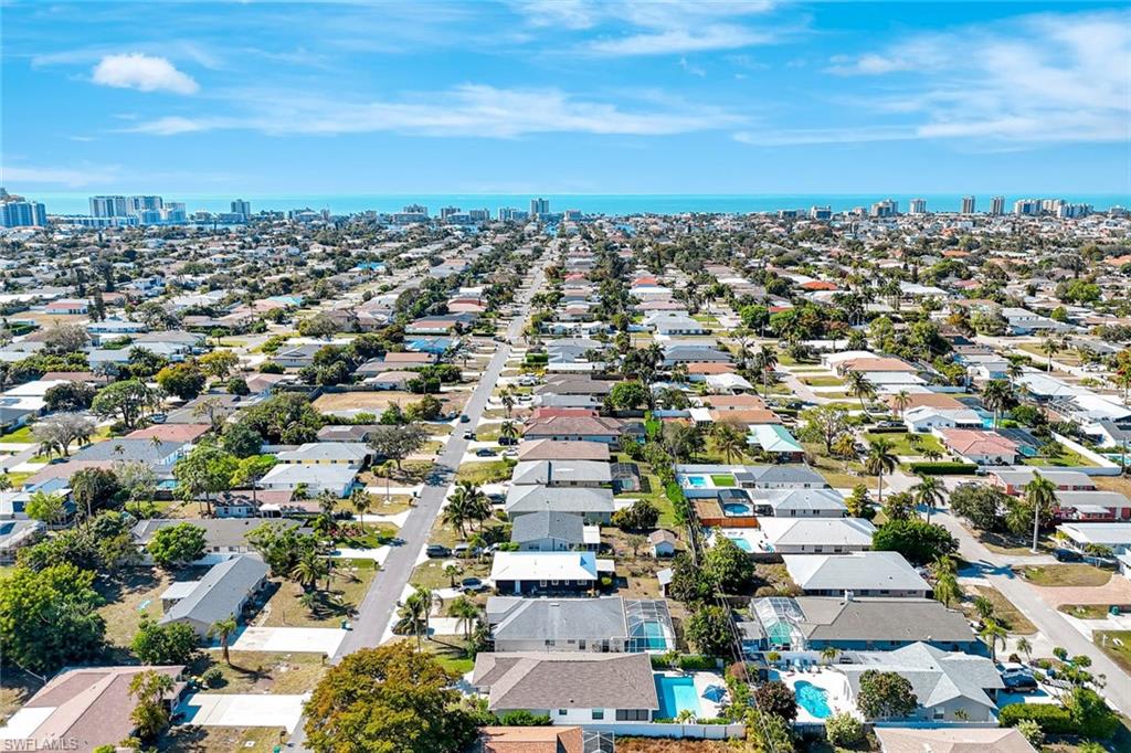 761 99th Avenue North Naples, FL 34108 - Photo 24 of 31 Aerial view of property and surrounding area with city skyline, a large body of water, and nearby suburban area