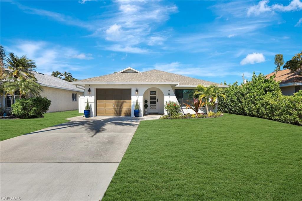 761 99th Avenue North Naples, FL 34108 - Photo 29 of 31 Ranch-style house with a front yard, concrete driveway, stucco siding, and a garage