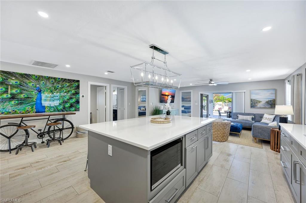 761 99th Avenue North Naples, FL 34108 - Photo 31 of 31 Kitchen featuring gray cabinetry, a center island, decorative light fixtures, open floor plan, and stainless steel microwave