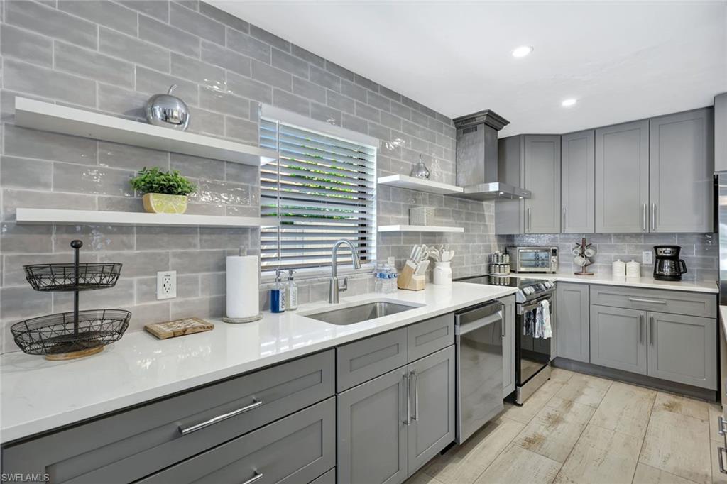 761 99th Avenue North Naples, FL 34108 - Photo 5 of 31 Kitchen with open shelves, gray cabinets, light stone countertops, stainless steel appliances, and recessed lighting