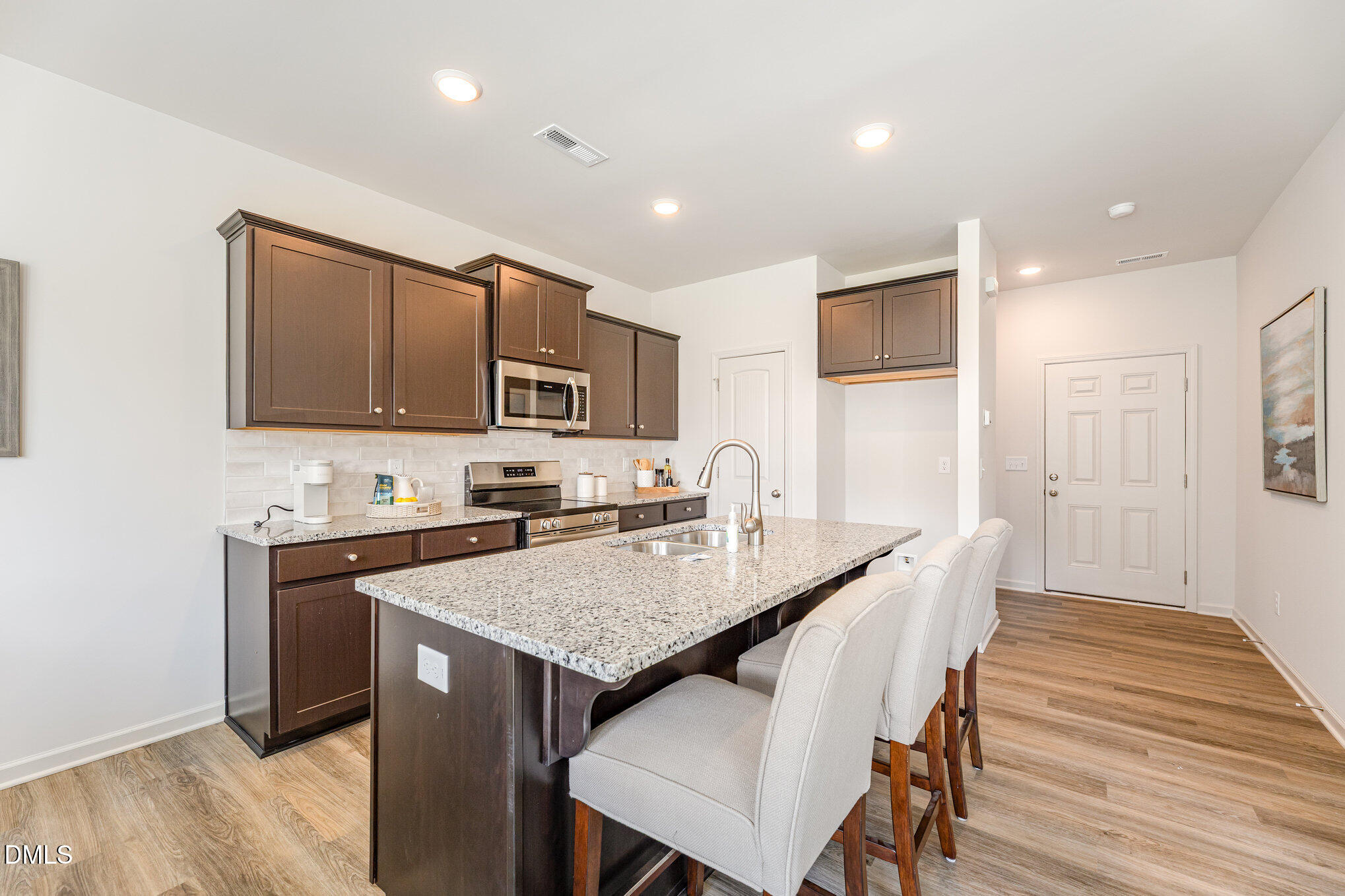 2302 Broad Street Durham, NC 27704 - Photo 7 of 16 a open kitchen with stainless steel appliances granite countertop a stove top oven a sink dishwasher a dining table and chairs with wooden floor