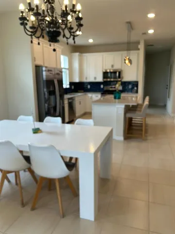 a dining room with wooden floor a chandelier a glass table and chairs